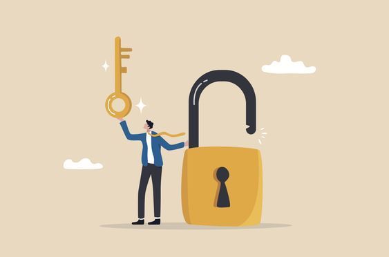 A man is holding a key in front of an open padlock.