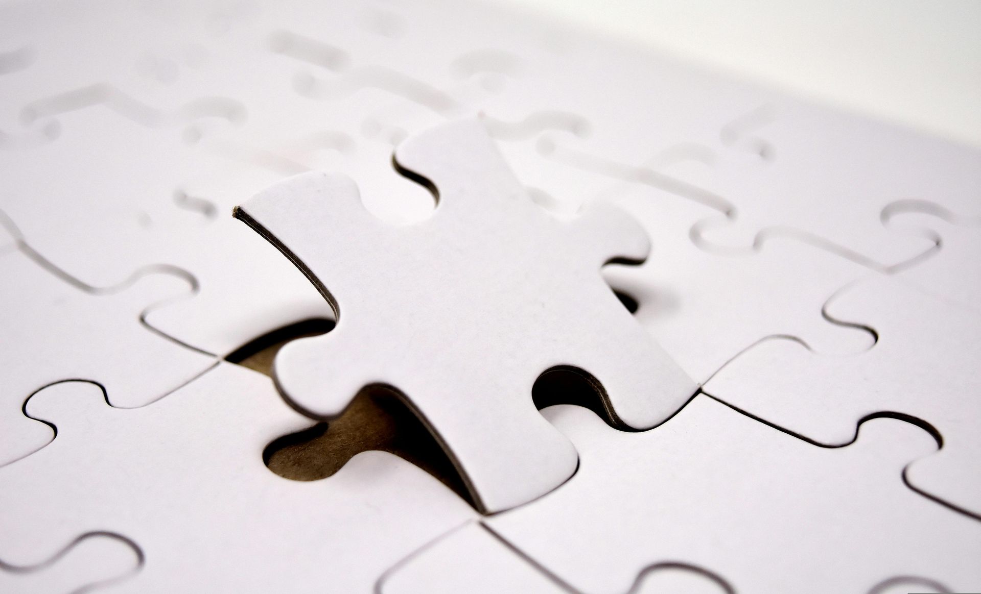 A white puzzle with a missing piece in the middle