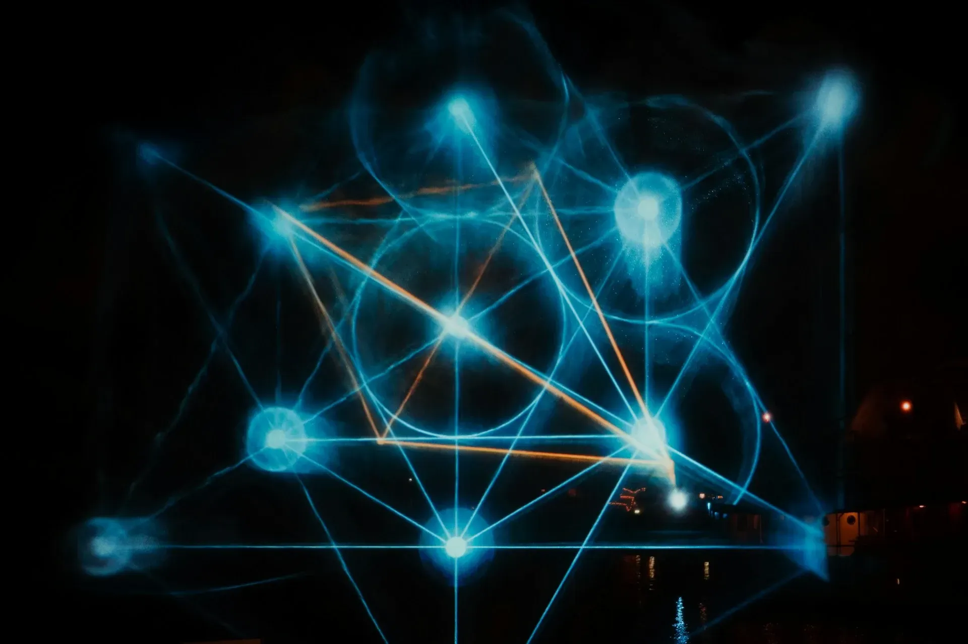 Glowing blue geometric shapes on a dark background; interconnected lines, spheres, and a triangle.